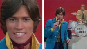 一位身穿藍色外套的1970年代歌手在紅色舞台上與鼓手一起表演。 — 荷里活 GIF 壁紙