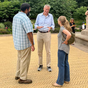 三人在公園的陽光磚砌廣場上聊天。