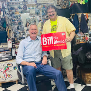 兩個微笑的男人，一個在裝飾過的房間裡舉著Bill de Blasio for Congress標語牌。 — 政治 壁紙