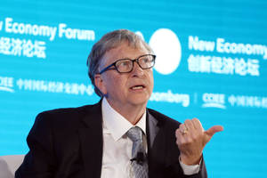 比爾·蓋茨在商業論壇上戴著眼鏡和西裝發言。