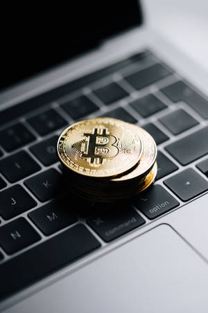 筆記本電腦鍵盤上的一堆金色比特幣硬幣