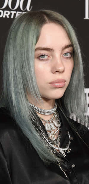 Billie Eilish 擁有綠色頭髮和層疊銀色項鍊，身穿黑色服裝。