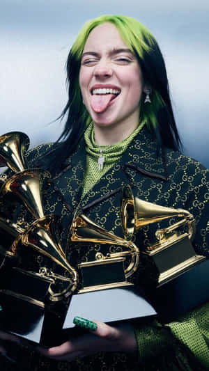 Billie Eilish 手持格林美獎項，露出搞笑的伸舌表情。