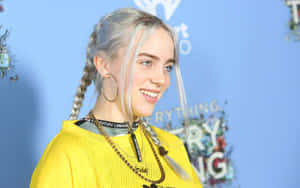 Billie Eilish 在活動中穿著黃色網眼上衣和編織頭髮。