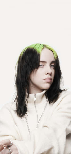 Billie Eilish 綠色頭髮穿著奶油色連帽衫，背景為白色。