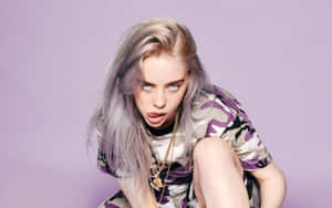 Billie Eilish 身穿紫色迷彩襯衫和金飾，背景為薰衣草色。