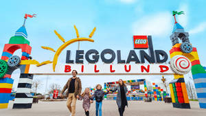 家庭在LEGO Billund主題公園入口微笑，周圍有色彩繽紛的LEGO結構。