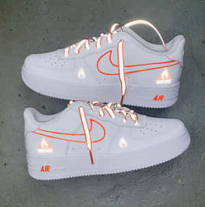 灰色混凝土上的白色Nike Air Force 1運動鞋，帶有橙色火焰細節。