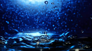 藍色水滴落入漣漪水中，背景模糊散景。 — 海洋 壁紙