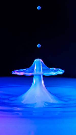 一顆發光的藍色水珠在深色背景下被捕捉到飛濺的瞬間。