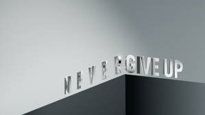 灰色牆上以金屬字母呈現的勵志短語never give up。