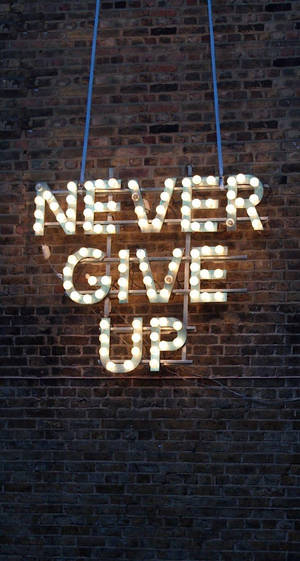 勵志霓虹燈牌，上面寫著 never give up，夜晚掛在磚牆上。
