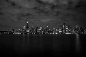 城市天際線的黑白夜景，燈光倒映在水面上。