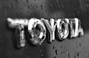 Toyota 汽車標誌特寫，表面帶有雨滴。 — MacBook Air 15 壁紙