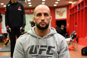 嚴肅的UFC戰士穿著灰色連帽衫坐在紅色更衣室中。