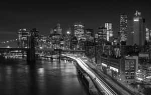 夜晚的布魯克林大橋，帶有燈光軌跡和黑白曼哈頓天際線。