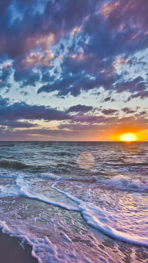 夕陽映照海洋，彩色雲彩和海浪拍打沙灘