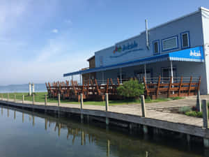 一間海濱餐廳，在平靜水邊的碼頭上有木製桌椅。