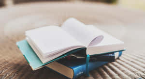 一堆書，其中一本打開，置於柳條表面，柔和光線下。