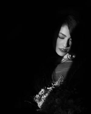一個閉著眼睛的女人在黑暗、戲劇性的肖像中拿著一束花。