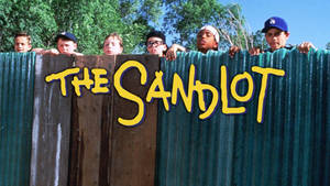 六名戴著棒球帽的男孩從綠色柵欄上方窺視，標題為「The Sandlot」。