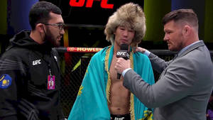 戴著皮草帽、身穿青綠色長袍的UFC拳手在八角籠內接受訪問。