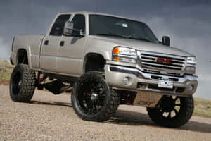 升高嘅銀色 GMC Sierra  pickup 貨車，黑色車輪，碎石路。