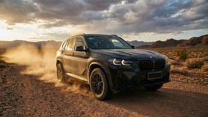 日落時分黑色BMW SUV在塵土飛揚的沙漠道路上行駛