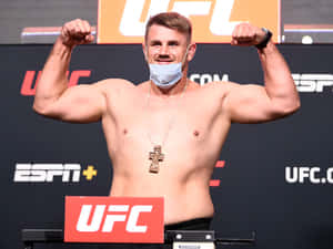 UFC拳手在稱重時彎曲手臂，戴著口罩和十字架項鍊