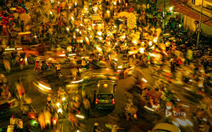 夜間城市街道充滿電單車和人們在溫暖燈光下的模糊動態。 — 唐人街 GIF 壁紙