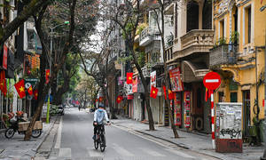 越南寧靜街道上的騎單車者，殖民建築和紅旗。