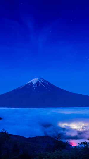 暮色中的富士山，下方有雲和遠處的燈光