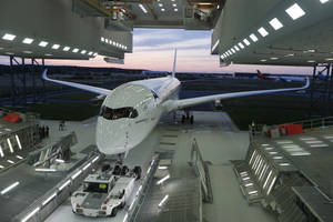 黃昏時機庫內的白色空中巴士A350飛機及地勤人員和車輛。