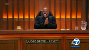 法官Steve Harvey在法庭桌後拍手微笑。