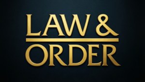黑暗背景上嘅金色 Law & Order 標誌，帶有金屬光澤同陰影。