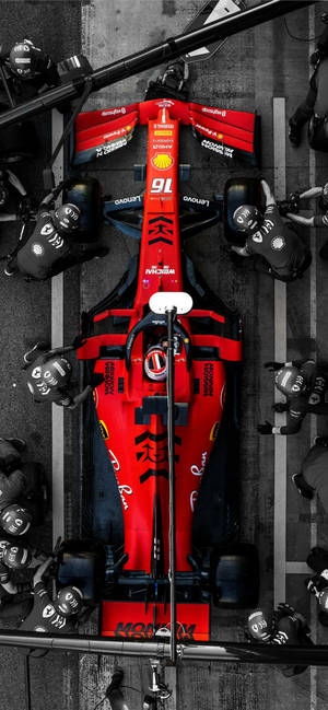 紅色法拉利F1賽車在賽道上由維修人員進行服務。