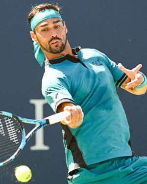 網球選手揮拍擊球，在強烈陽光下擊中黃色網球。