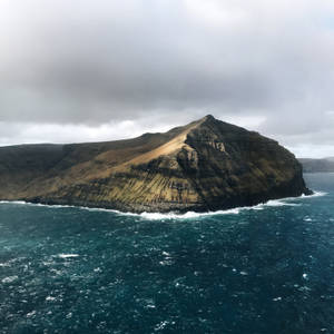 灰色天空下暴風雨海洋中的崎嶇懸崖島嶼