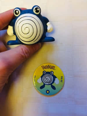 手拎住 Psyduck 公仔喺官方 Pokémon 徽章上面。 — 寵物小精靈電話 壁紙