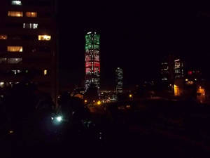 城市中一座燈火通明的摩天大樓的夜景，周圍有建築物。 — 夜晚 GIF 壁紙