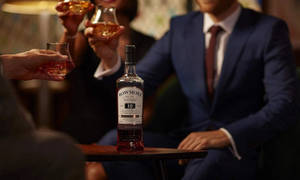 人們圍著一瓶Bowmore 19年威士忌舉杯祝酒。