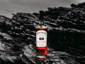 一瓶Bowmore 15年威士忌放在深色海岸岩石上。