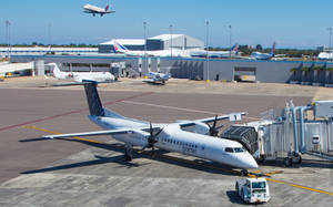 一架波特航空的飛機停靠在機場閘口，另一架飛機正在起飛。