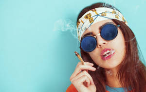 戴太陽眼鏡和頭帶的女性，手持大麻煙並呼出煙霧。