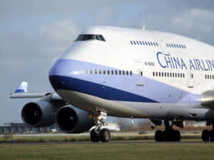 中華航空波音747飛機在跑道上，有草地和雲。