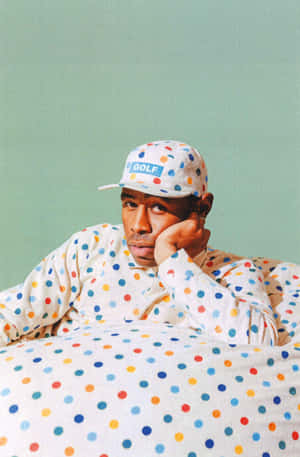 穿著波點睡衣和帽子的男人在綠色牆壁前的床上休息。 — Tyler the creator GIF 壁紙