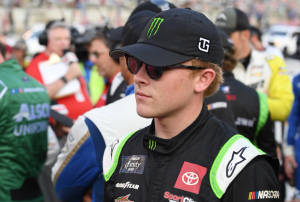 NASCAR車手在賽道上穿著賽車裝備，與團隊和觀眾一起。