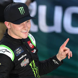 身穿賽車裝備的NASCAR車手微笑著指向鏡頭。