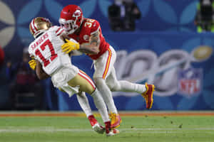 NFL球員在體育場燈光下的草地上被對手擒抱。