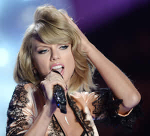 Taylor Swift 在舞台上用手撥弄頭髮並拿著麥克風唱歌